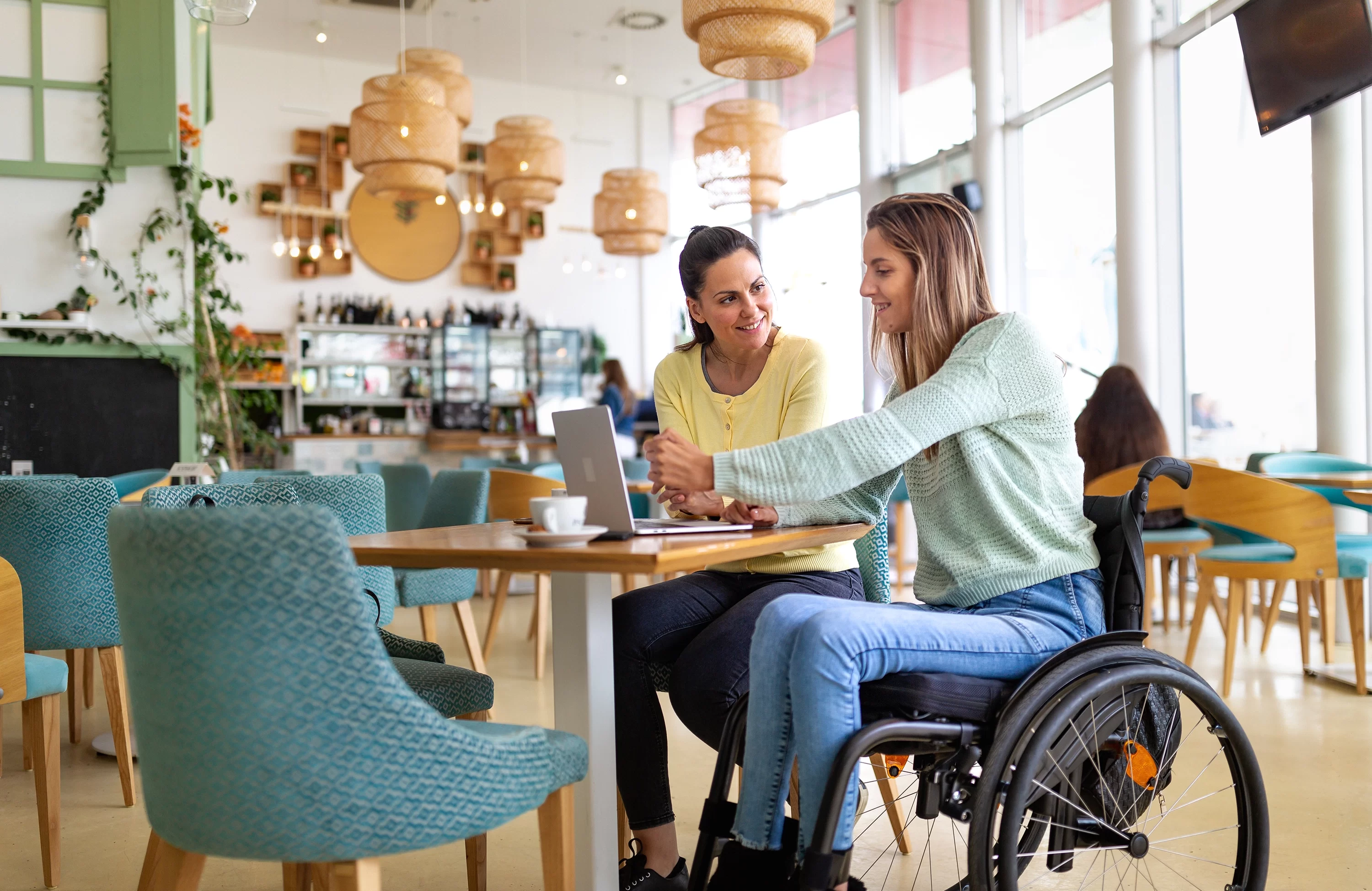 Lady in wheelchair in cafe talking with another lady