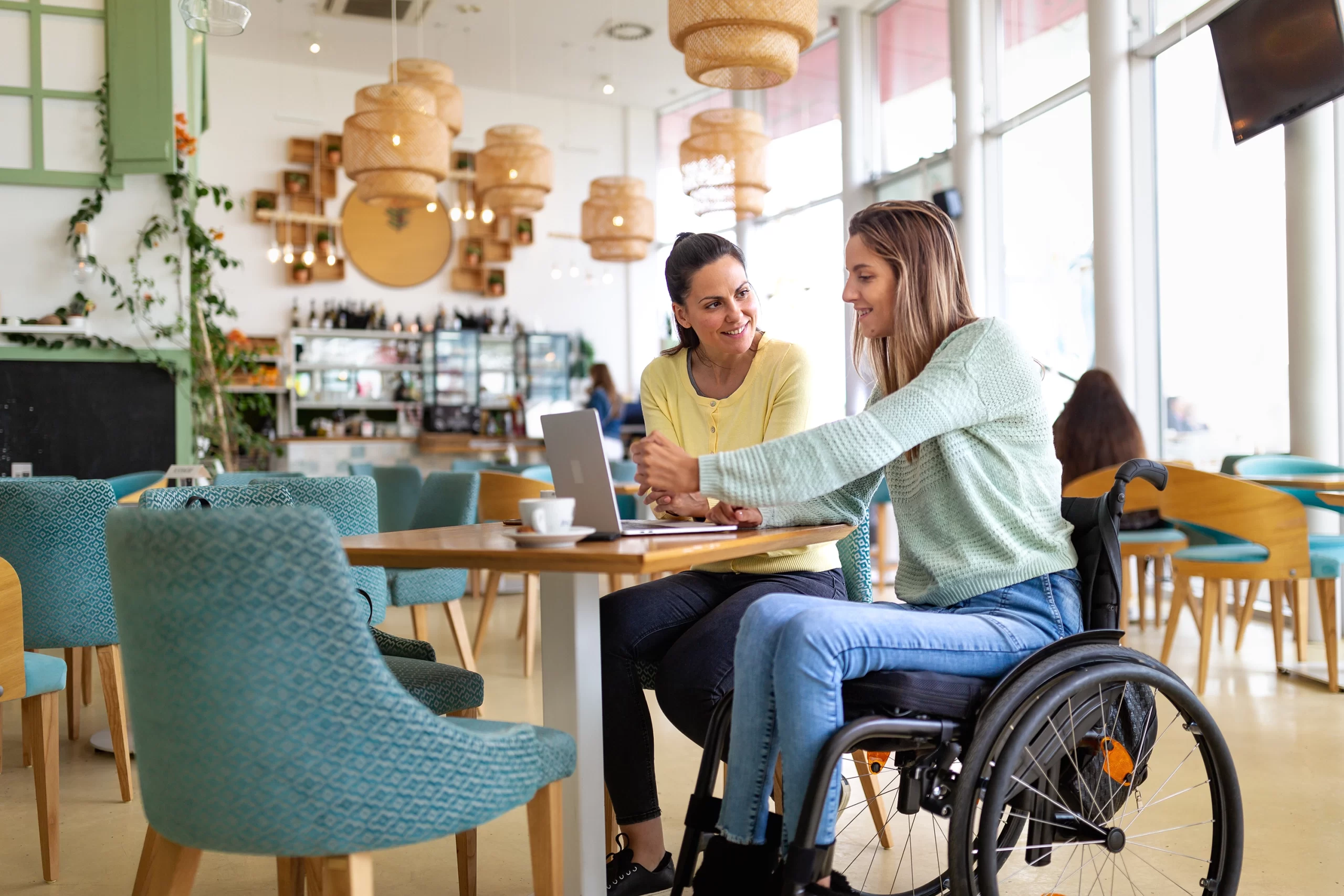 Lady in wheelchair in cafe talking with another lady