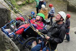 A young person abseiling down a rock face in a wheelchair